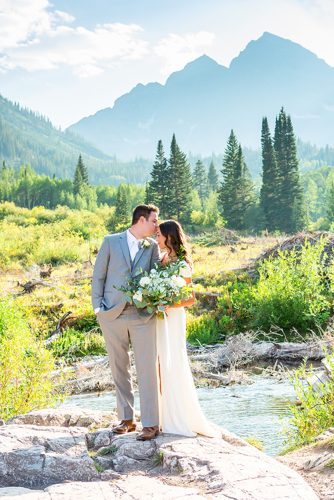 couple snuggling in front of Maroon Bells during their mountain elopement.