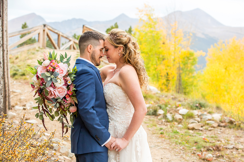 Catherine and Trevor embrace on their wedding day in front of mountains and fall colors.