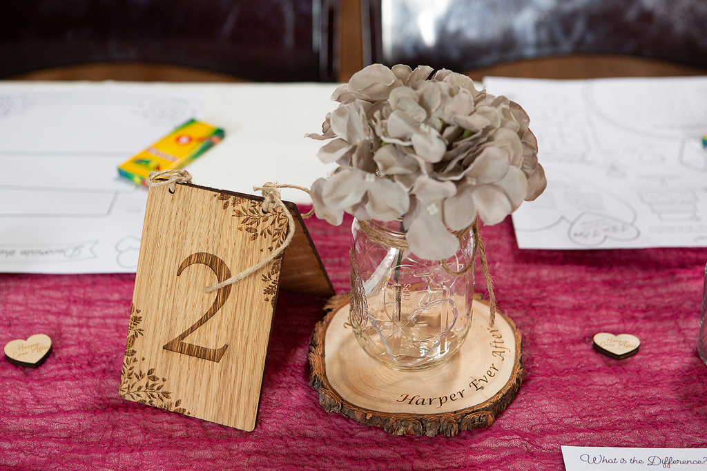 Close up of wedding center piece with wooden sign and flowers.