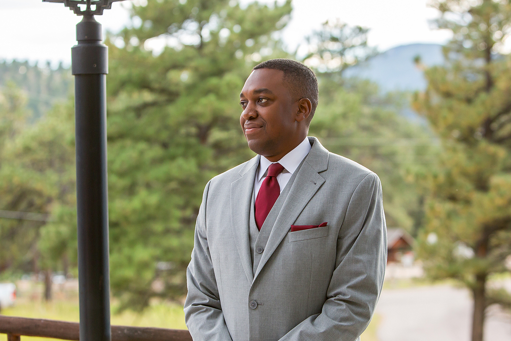 Groom smiles as he sees his bride walk down the aisle in Evergreen, CO.