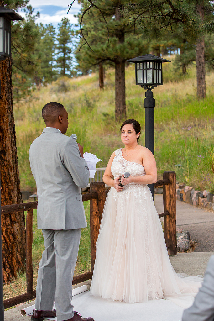 Bride listens to vows surrounded by pine trees in the mountains.