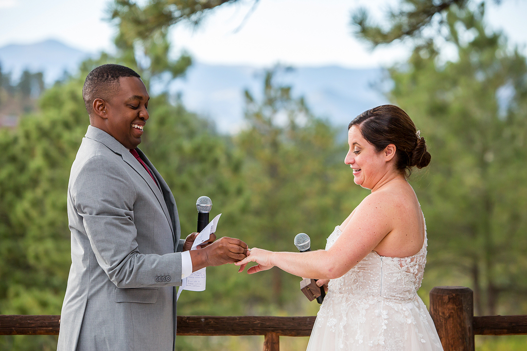 Bride and groom exchange rings in Evergreen in front of a mountain view.