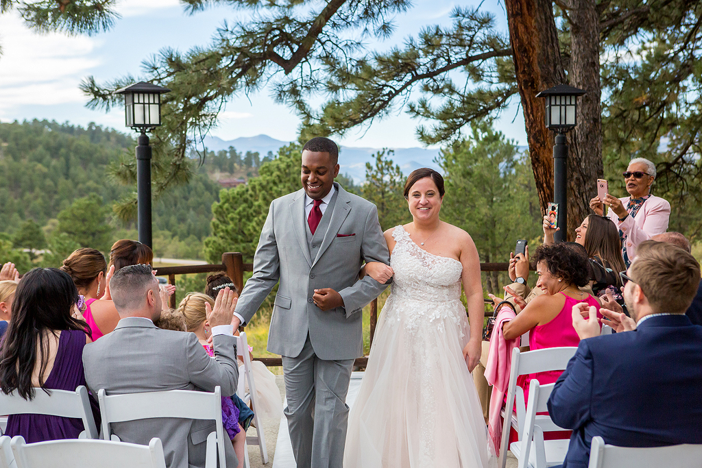 Bride and groom smile as they walk back down the aisle at the end of their ceremony.