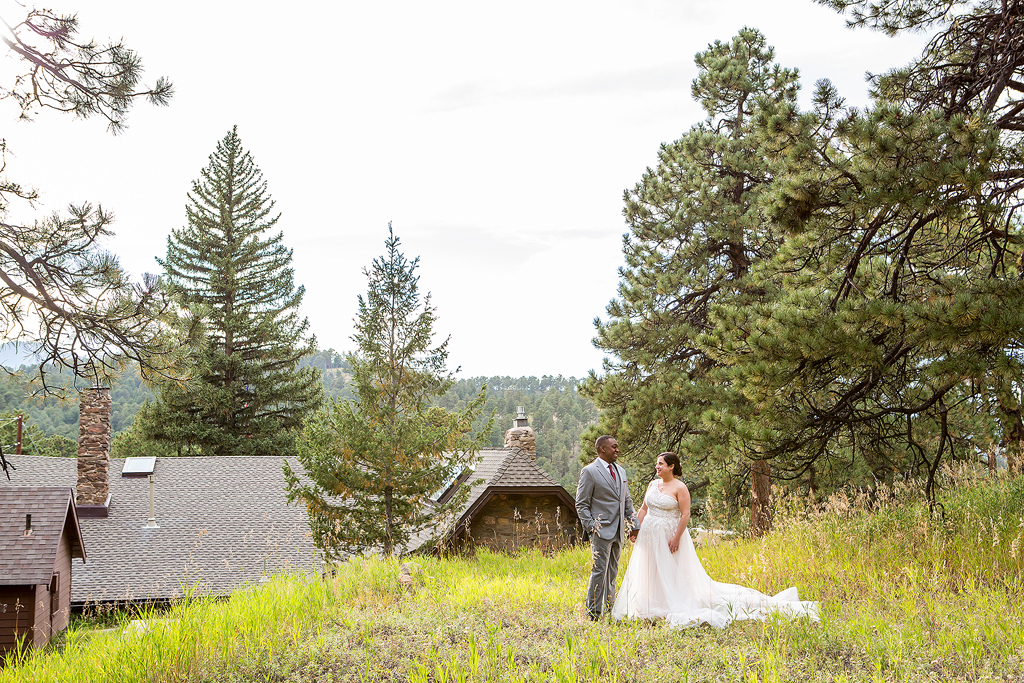 Bride and groom stand in a meadow with rolling his behind in Colorado.