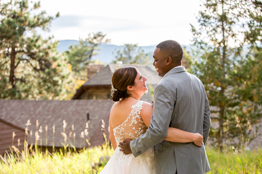 Bride and groom surrounded by pine trees with Chief Hosa Lodge in the background.