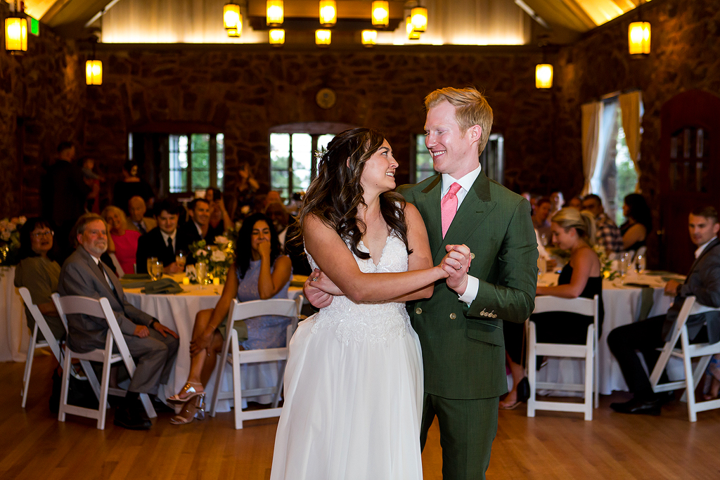 bride and groom look at each other with guests in the background during their first dance in Golden CO.