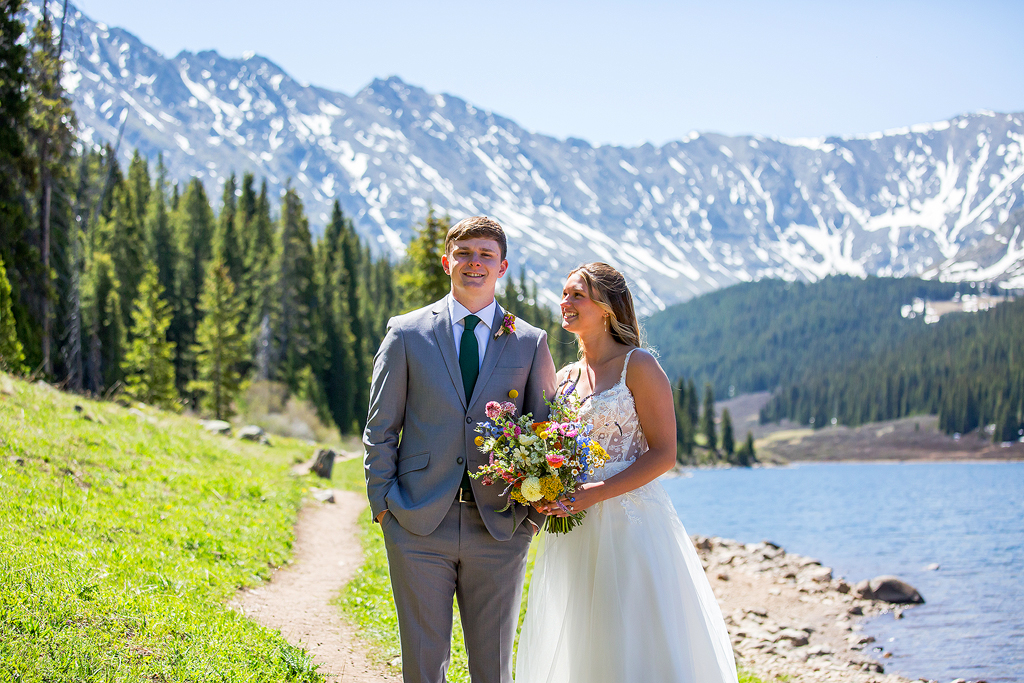 bride hugs her groom with an alpine lake and mountain backdrop during their elopement.