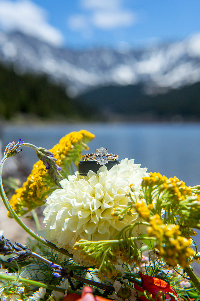 Close up of wedding rings in front of an alpine lake in Colorado.