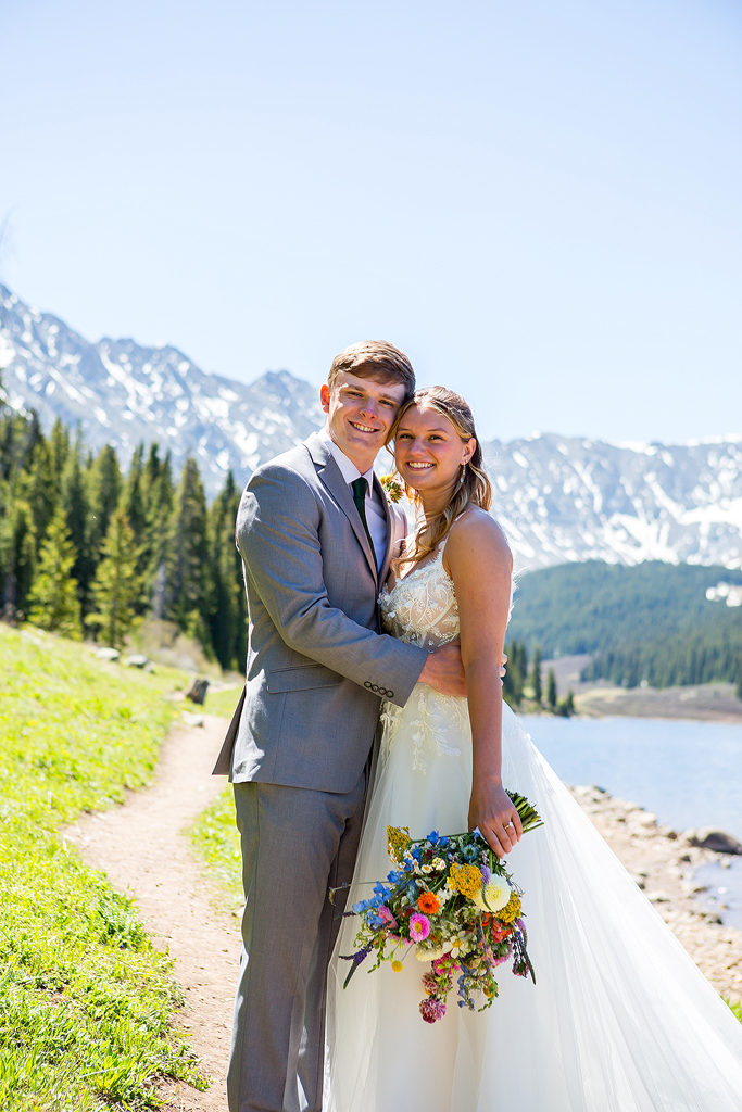 bride and groom embrace on a mountain trail during their Colorado elopement.