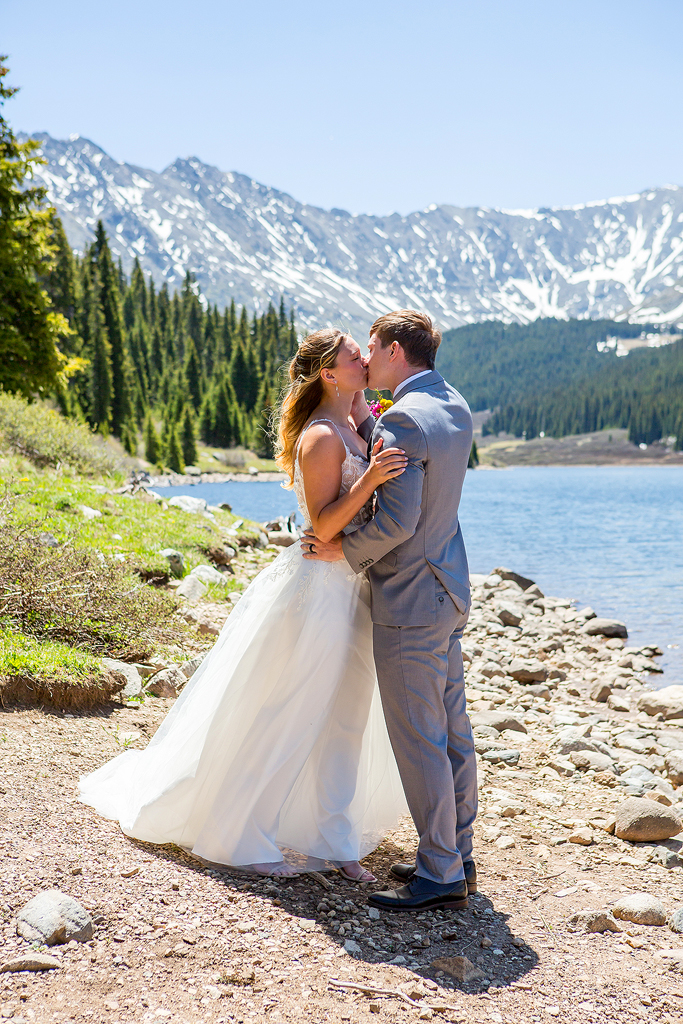 Bride and Groom kiss after elopement ceremony on the beach of an alpine lake.