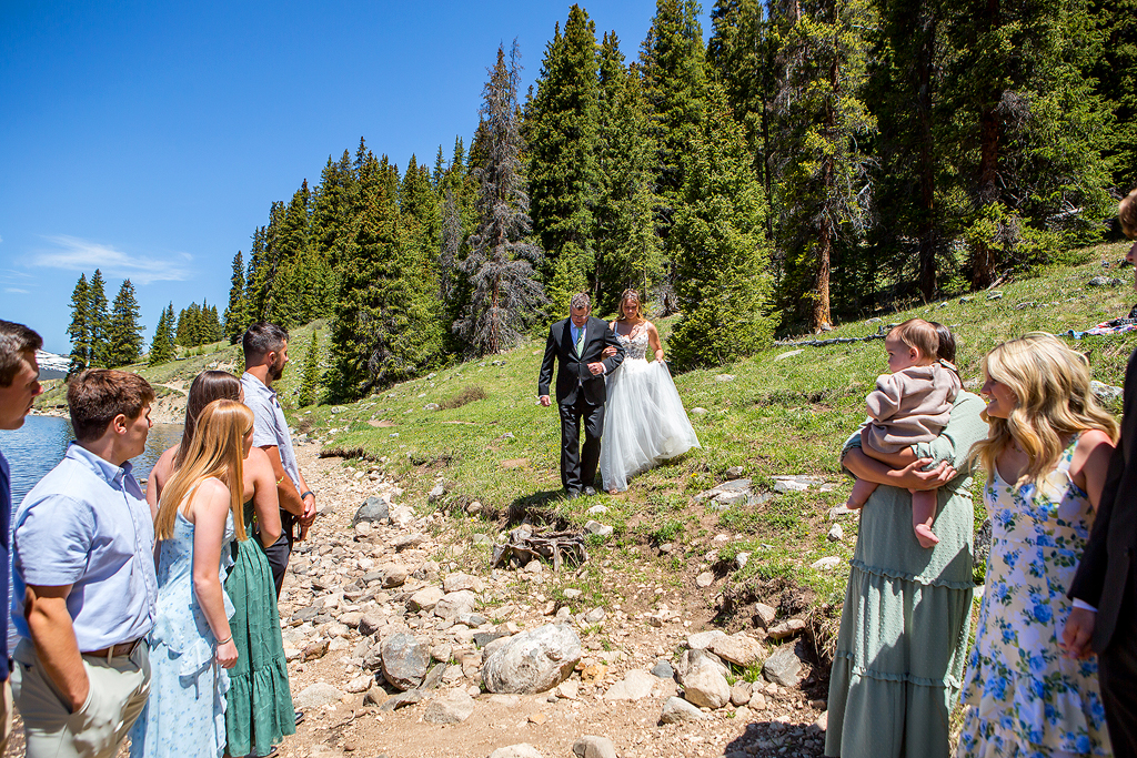 Bride walks down the beach with her dad during this mountain elopement.