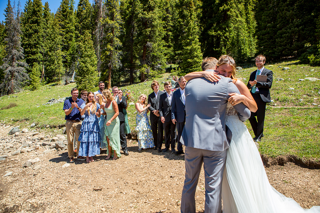 bride and groom hugs after elopement ceremony is over with guests in the background.