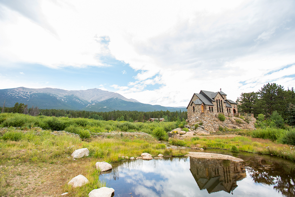 Wide view of the Chapel on the rock in Allenspark with Longs Peak in the background and reflection in a creek