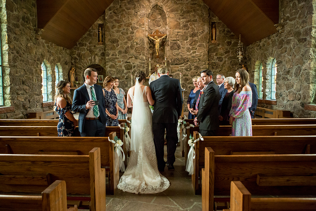 Wide view of bride walking down the aisle in the Chapel on the Rock in Colorado