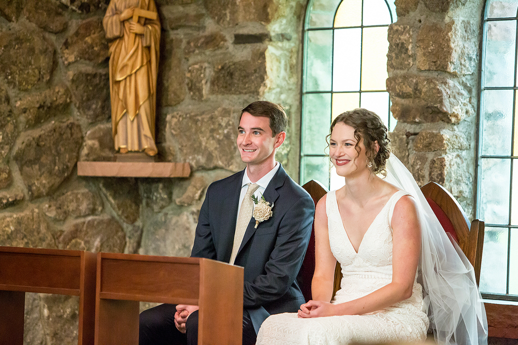 Bride and groom smile during ceremony at Camp St Malo in Colorado near Estes Park.