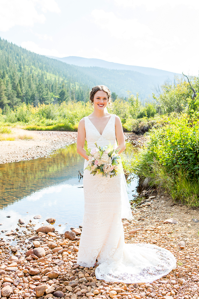 Bride portrait next to a creek with mountains behind in Allenspark, CO.