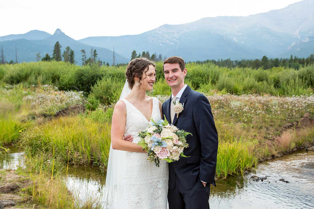 Erin and Chip during their wedding in front of a creek at Camp St Malo near Estes Park