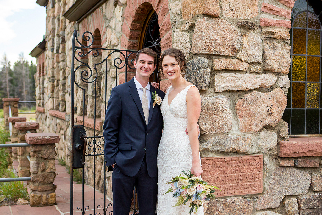 Bride and groom stand in front of the stone arch at Camp St Malo