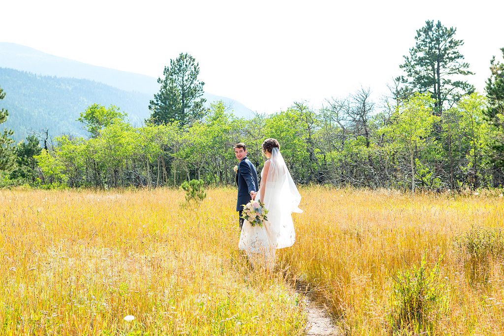 Erin and Chip walk through a Colorado meadow on their wedding