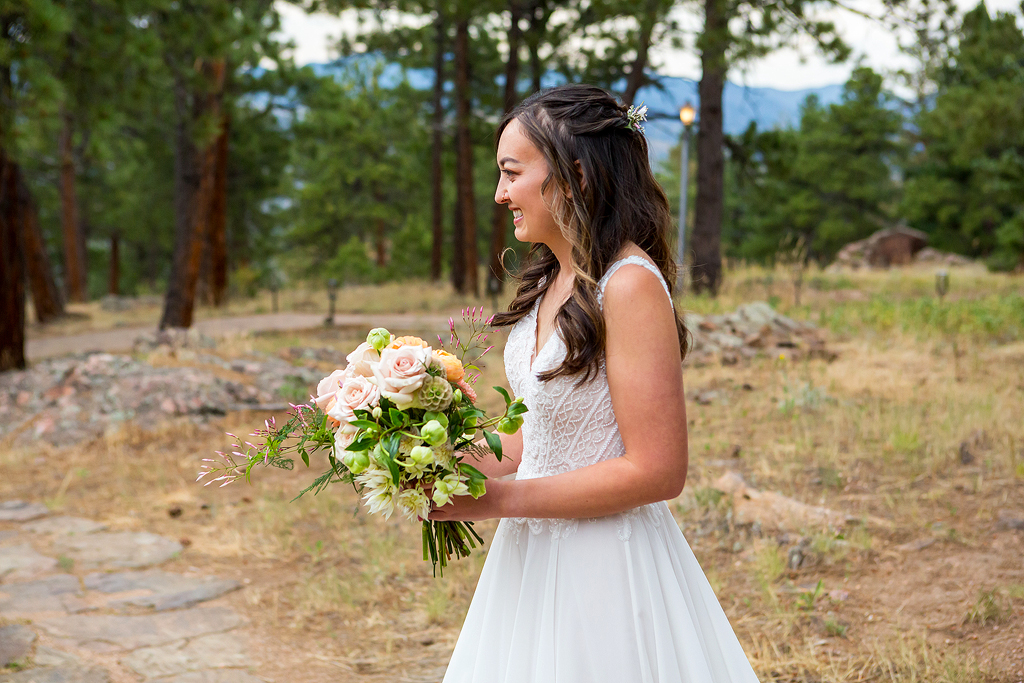 Bride smiles as she walks through the forest for their first look.