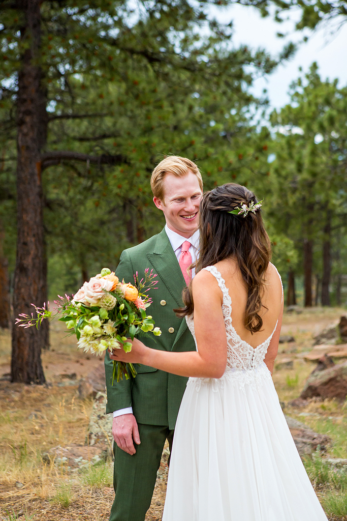 Groom smiles as he see his bride for the first time on a forest trail in Golden, CO.