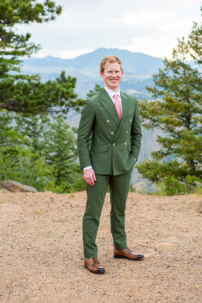 Groom portrait framed by pine trees with a scenic mountain view.