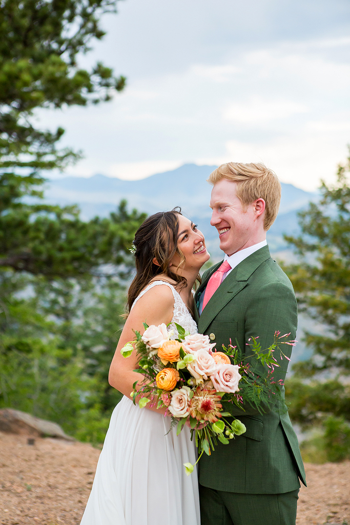 Bride and groom laugh with the mountains behind them.