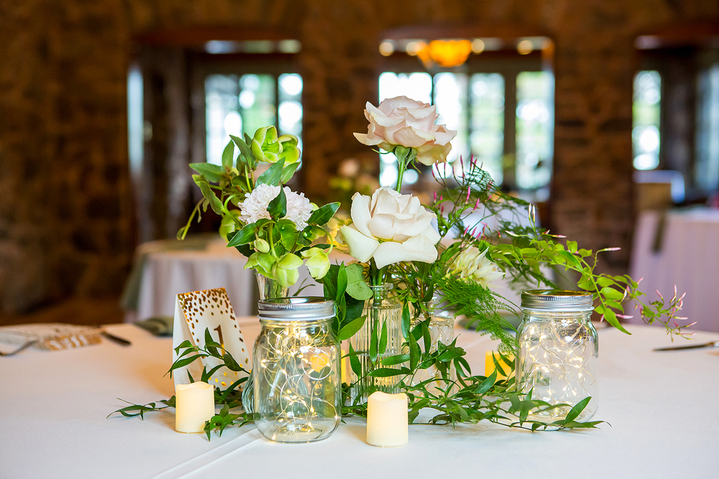Table center piece with lights, flowers and mason jars at Boettcher Mansion.