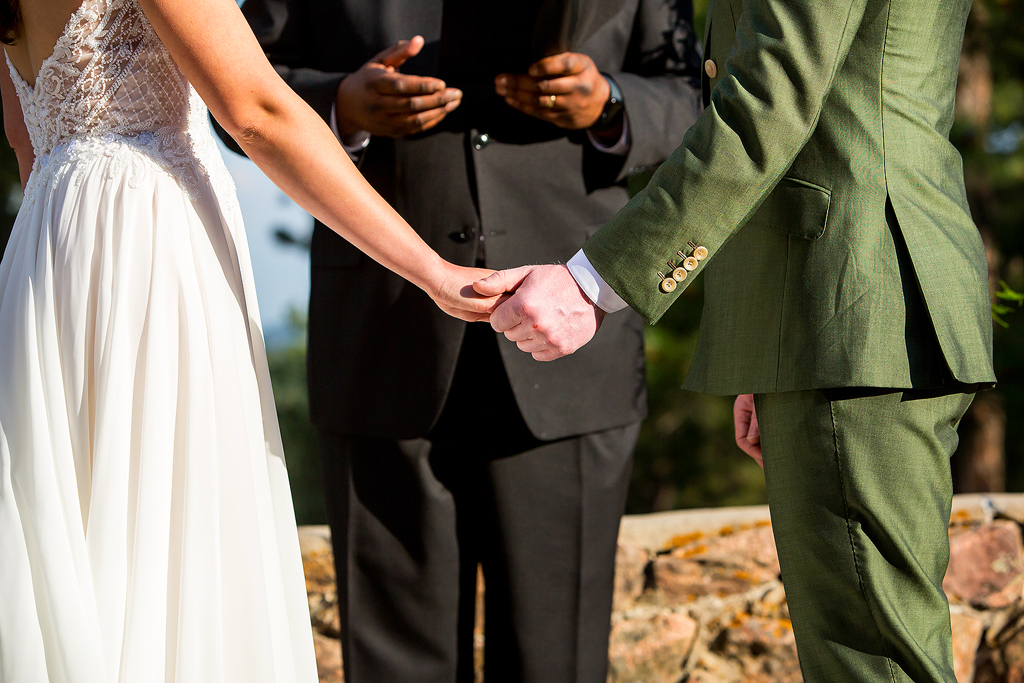 Close up of couple holding hands during their wedding ceremony.