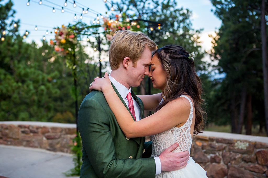 The sun sets at Boettcher Mansion as bride and groom embrace on the stone patio.