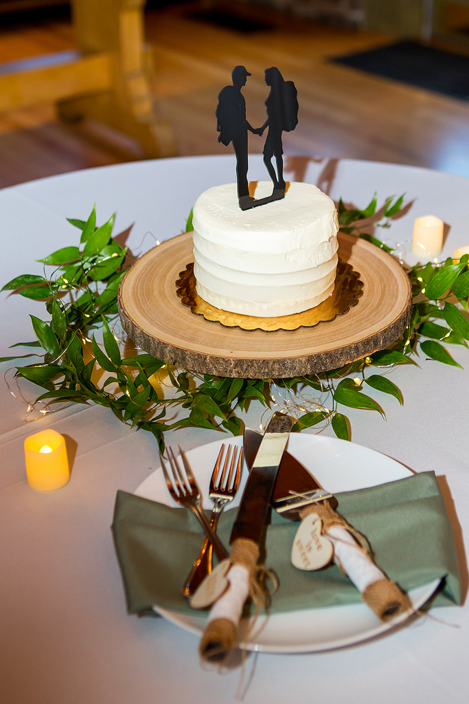 Close up of wedding cake with cake topper of hiking couple.