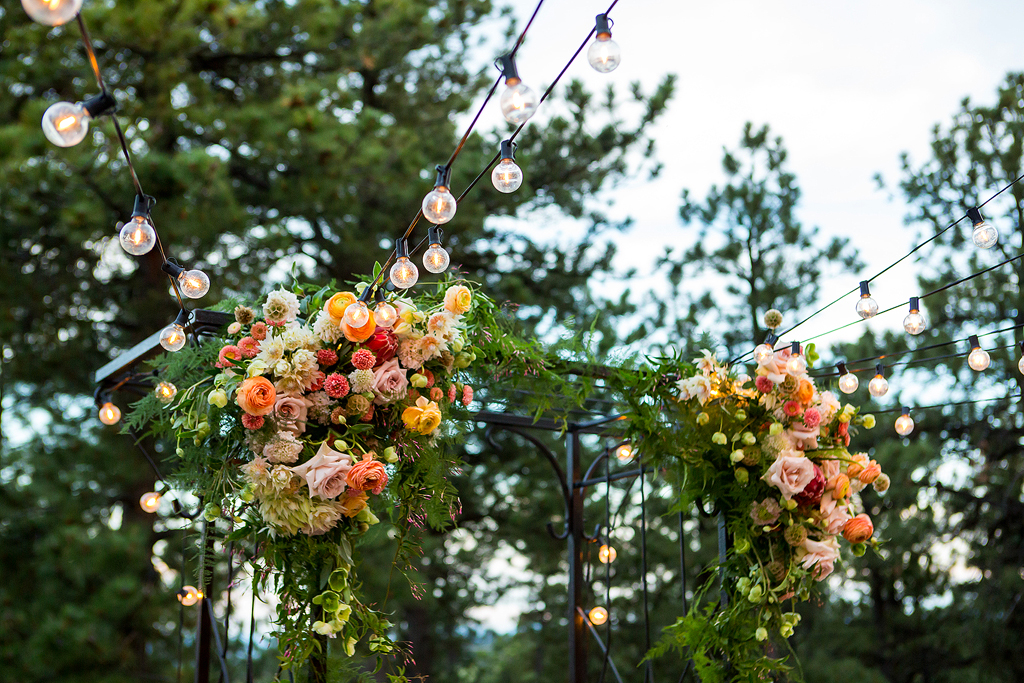 Close up of lights and floral decoration in ceremony area.