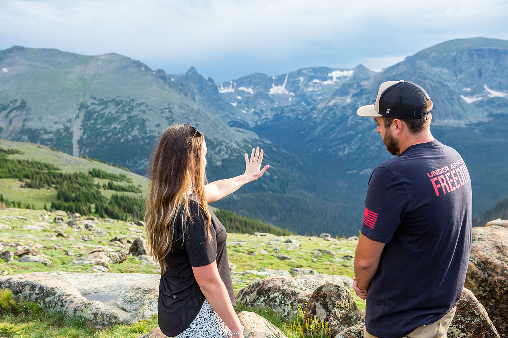 Sabrina holds out her hand in front of mountains with her engagement ring.