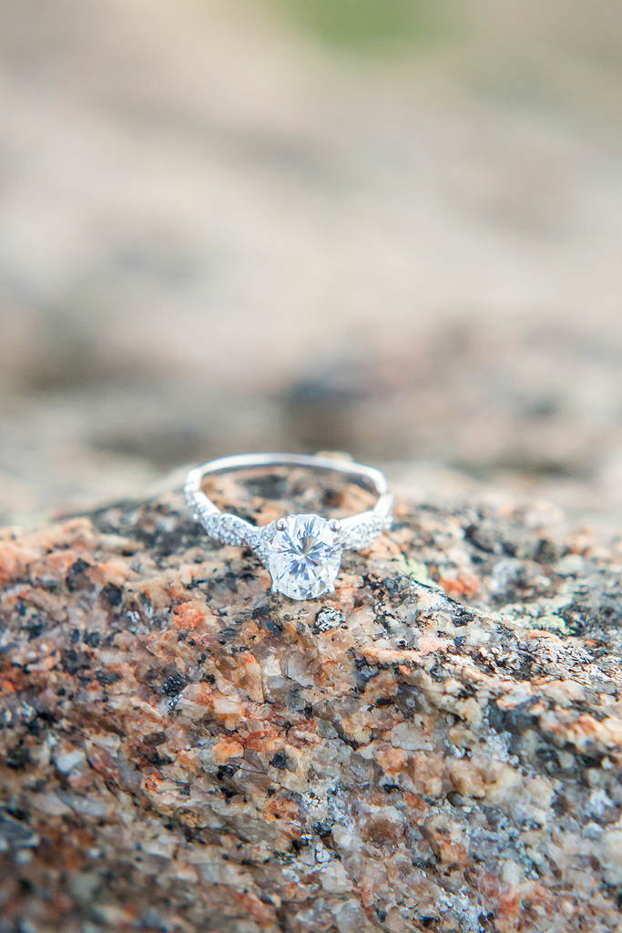Close up of engagement ring on a granite rock.