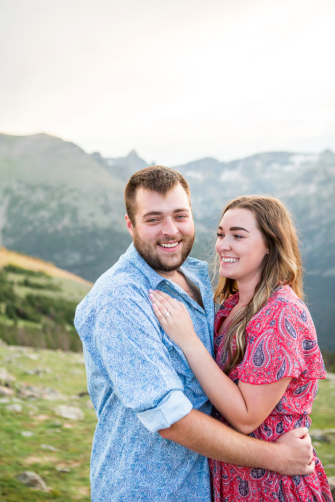 Couple snuggles and laughs in a green field in the Colorado alpine tundra.