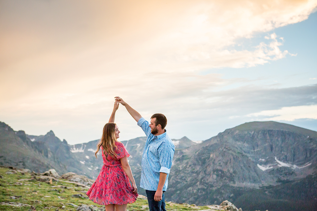 Zach twirls Sabrina after their proposal as the sky changes color as sunset in RMNP, Colorado.