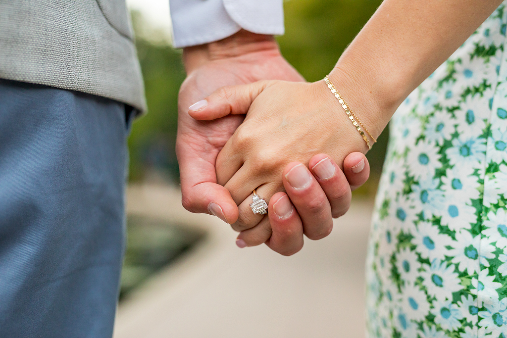 Close up of engagement ring and couple's hands.