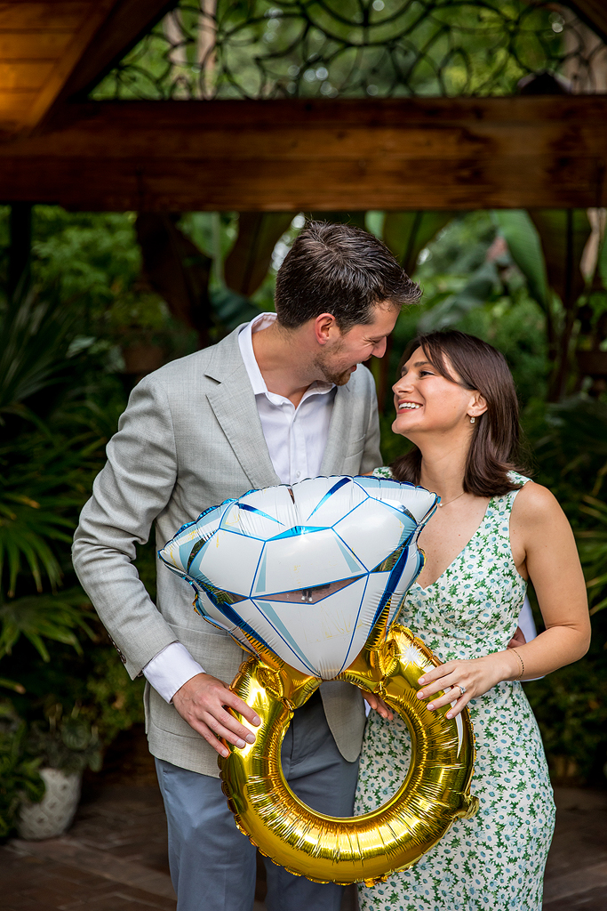 Couple holds the engagement ring balloon while showing off the real engagement ring too.