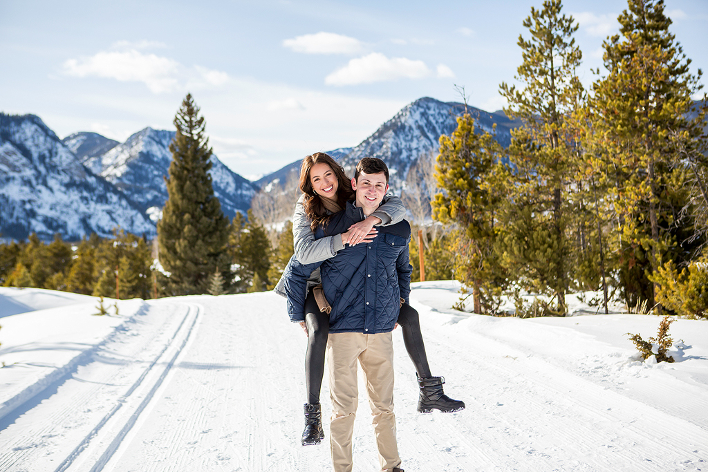Stephanie jumps on Scott's back and smiles during their winter proposal near Breckenridge in Colorado.