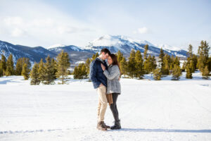 Scott and Stephanie snuggle in front of a snowy mountain peak after their engagement.