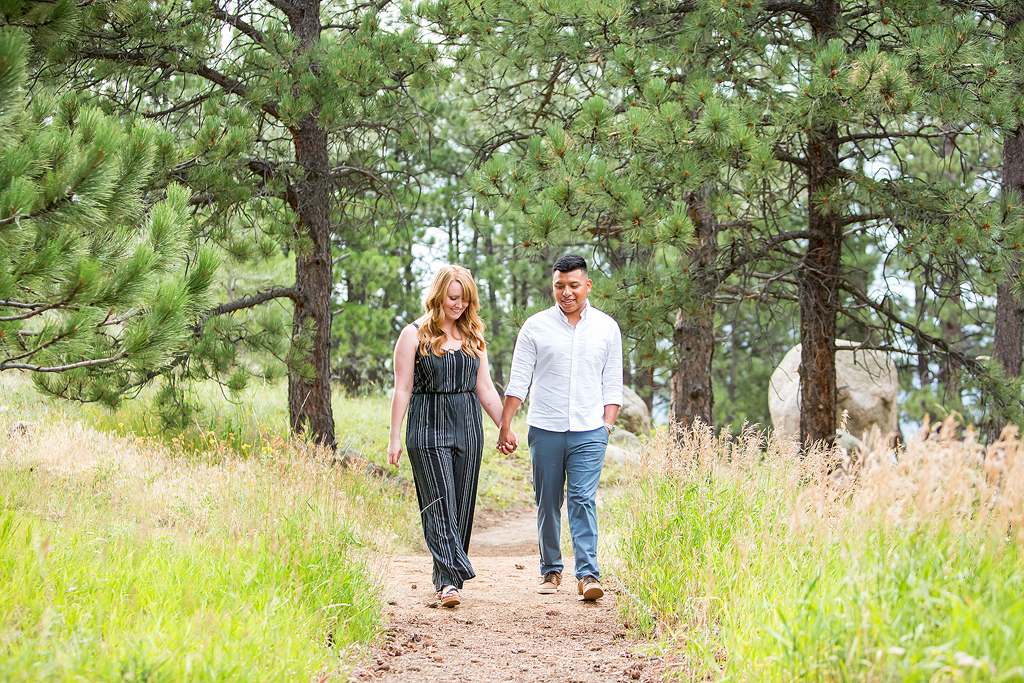 Luis and Nicole walk through a forest in Boulder after getting engaged in Colorado.