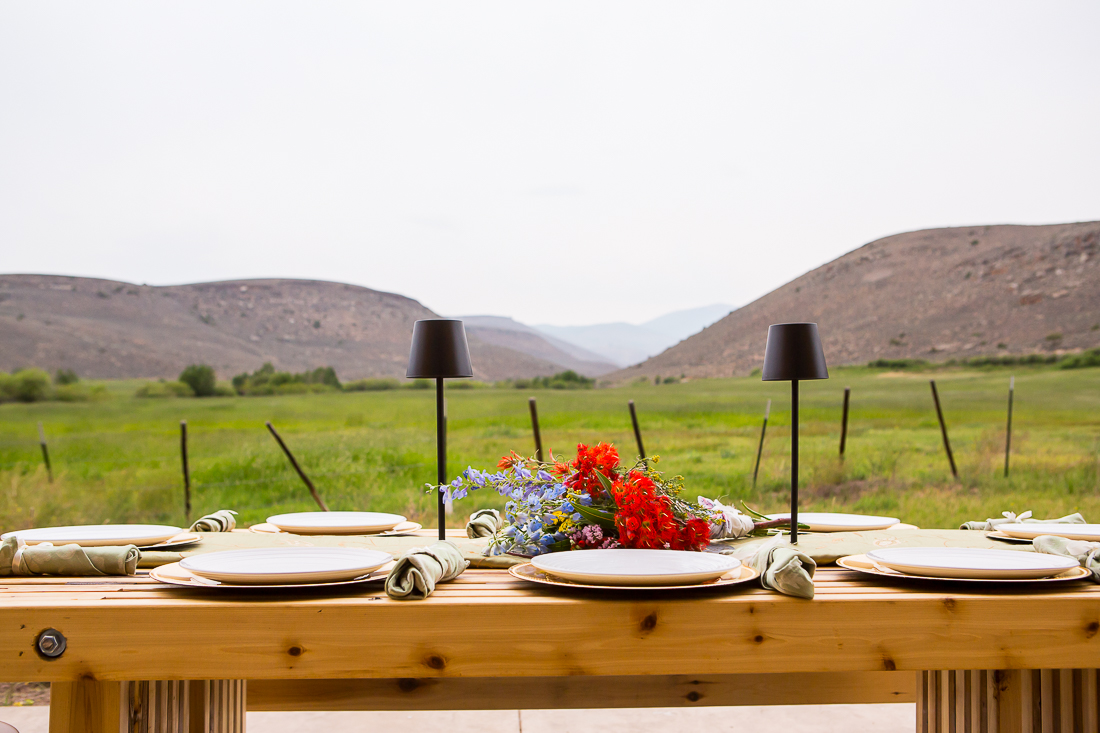 Elopement dinner table setup wtih wildflowers in the center and mountains in the background.