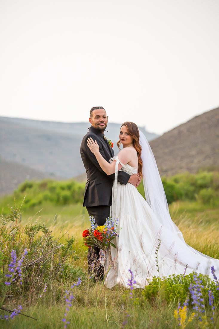 Bride and groom smile in front of mountains near Gunnison Colorado during their elopement.